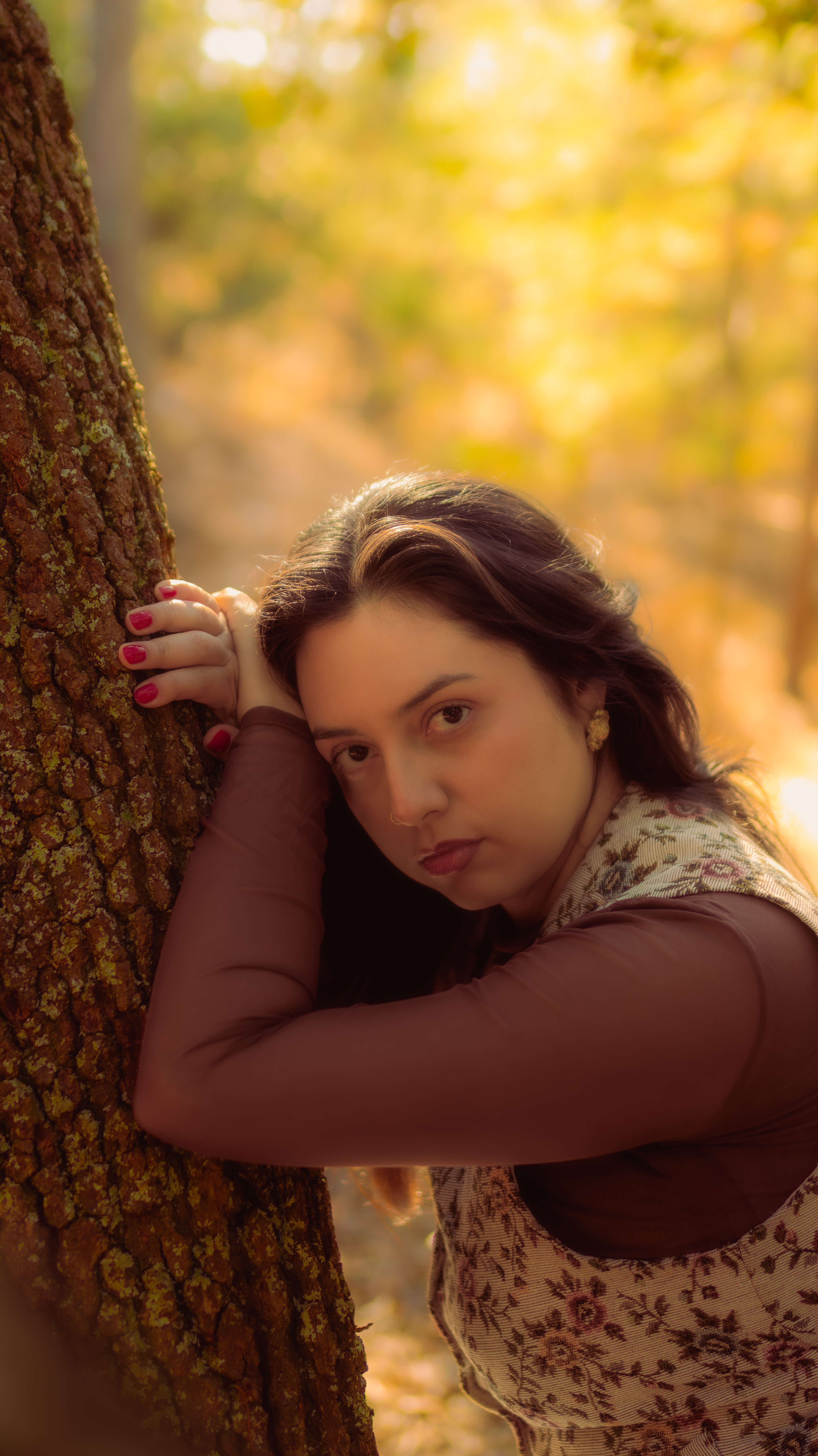 Woman leaning against a tree with arms crossed